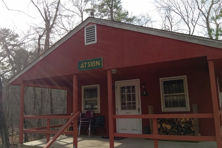 Red cabin with a porch, labeled 'ATSION', surrounded by trees.