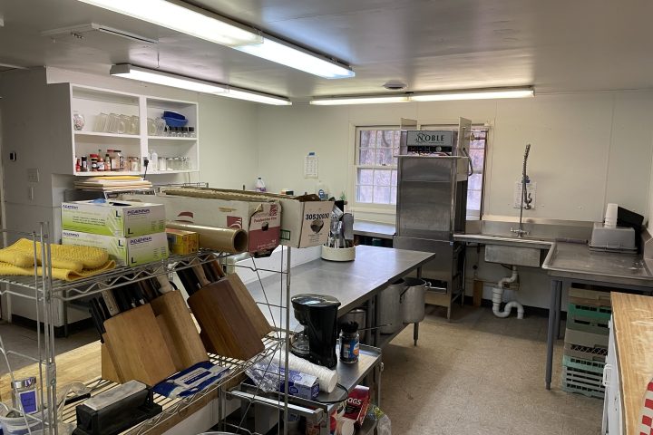 Commercial kitchen with metal shelves, cutting boards, and a stainless steel sink.