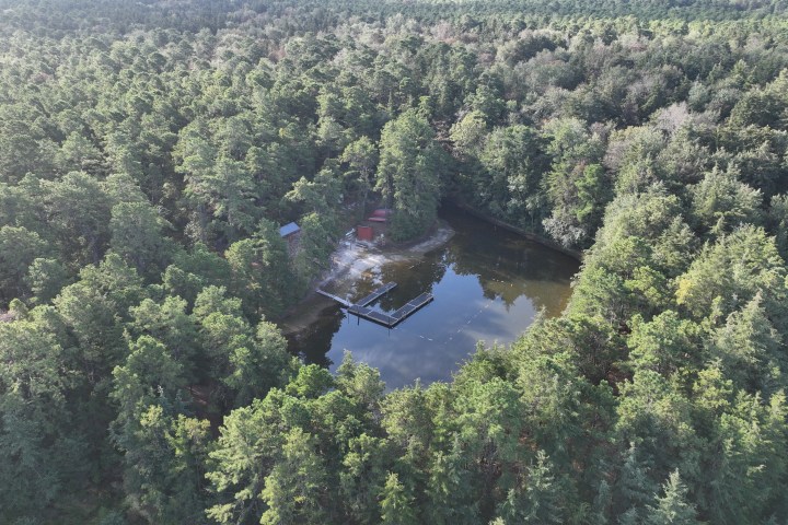 Aerial view of a small lake surrounded by dense forest.